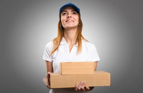 Delivery woman looking up on grey background