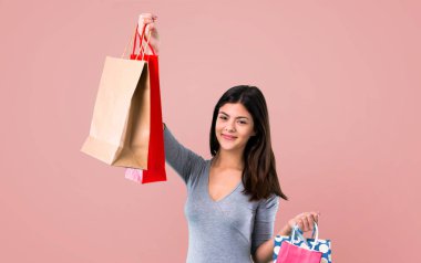 Pembe bir arka plan üzerinde alışveriş çantası ile genç kız