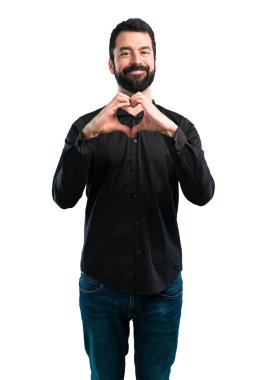 Beyaz arka plan üzerinde bir kalp elleriyle yapma sakallı yakışıklı adam