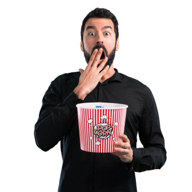 Popcorns beyaz arka plan üzerinde yemek sakallı yakışıklı adam