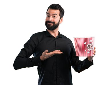 Popcorns beyaz arka plan üzerinde yemek sakallı yakışıklı adam