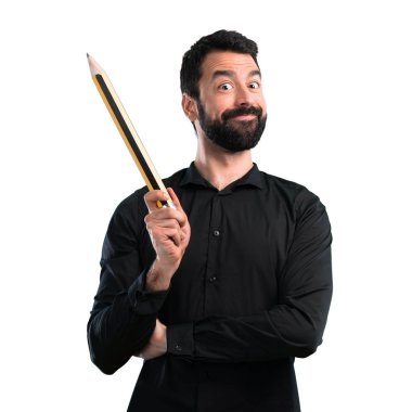 Beyaz arka plan üzerinde büyük bir kalem tutan sakallı yakışıklı adam