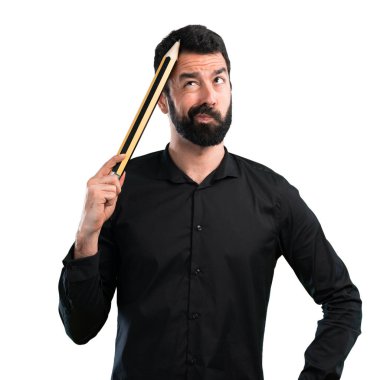 Beyaz arka plan üzerinde büyük bir kalem tutan sakallı yakışıklı adam