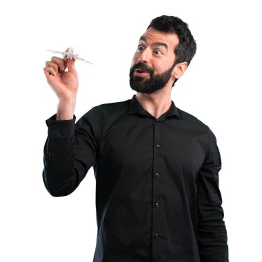 Beyaz arka plan üzerinde bir oyuncak uçak holding sakallı yakışıklı adam