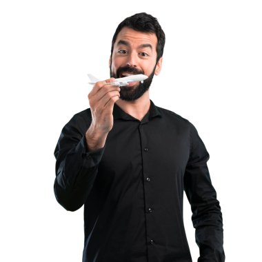 Beyaz arka plan üzerinde bir oyuncak uçak holding sakallı yakışıklı adam