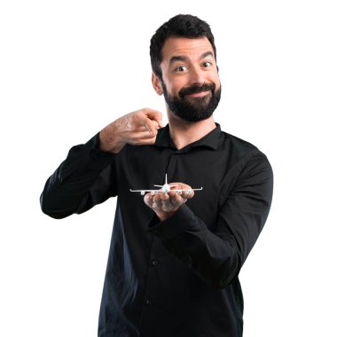 Beyaz arka plan üzerinde bir oyuncak uçak holding sakallı yakışıklı adam