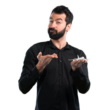 Beyaz arka plan üzerinde bir oyuncak uçak holding sakallı yakışıklı adam