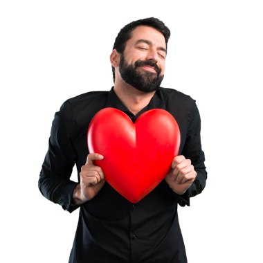 Beyaz arka plan üzerinde tutmak bir kalp oyuncak sakallı yakışıklı adam
