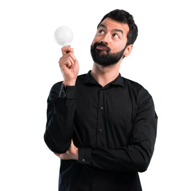 Bir ampul beyaz arka plan üzerinde tutarak sakallı yakışıklı adam