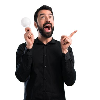 Bir ampul beyaz arka plan üzerinde tutarak sakallı yakışıklı adam