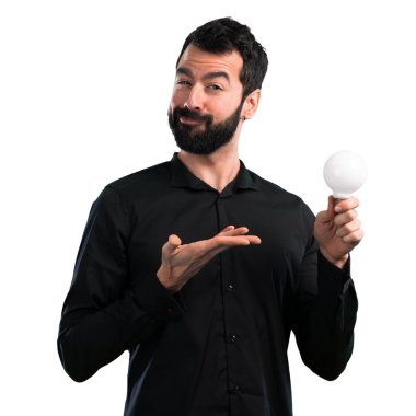 Bir ampul beyaz arka plan üzerinde tutarak sakallı yakışıklı adam