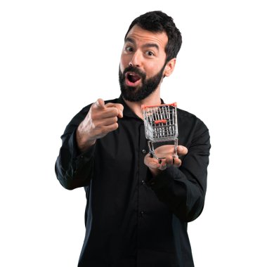 Beyaz arka plan üzerinde tutmak bir süpermarket arabası oyuncak sakallı yakışıklı adam