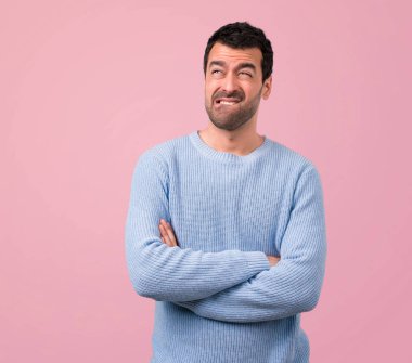 Yakışıklı adam şüpheleri ve pembe bir arka plan üzerinde karıştırmayın yüz ifadesi ile