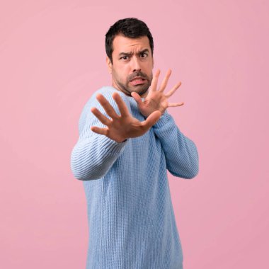 Biraz gergin ve korkmuş pembe bir arka plan üzerinde yakışıklı adamdır