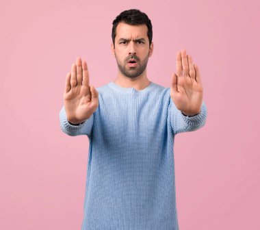 Yakışıklı adam yapma dur jestle elinde pembe bir arka plan