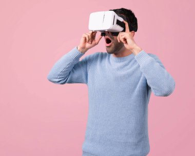 Mavi kazak Vr gözlükle olan adam. Pembe bir arka plan üzerinde sanal gerçeklik deneyimi