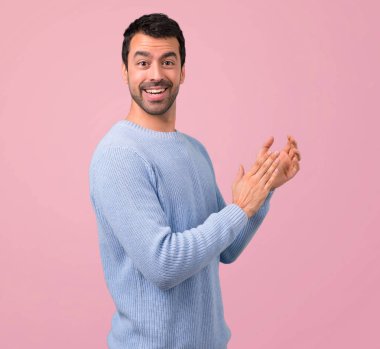 Man with blue sweater applauding after presentation in a conference on pink background clipart
