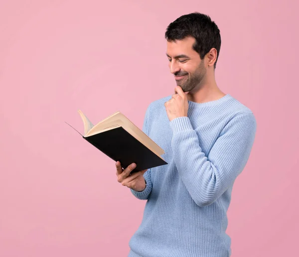 Человек Синем Свитере Держит Читает Книгу Розовом Фоне — стоковое фото