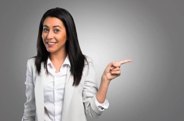 Lateral gri arka plan üzerinde işaret eden güzel bir kadın