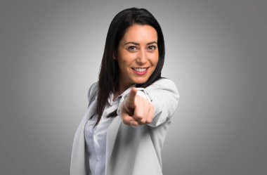 Gri arka plan üzerine açık işaret eden güzel bir kadın