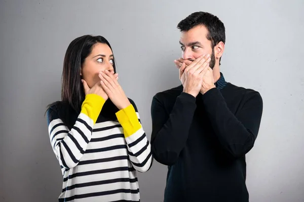 Couple covering their mouth on grey background