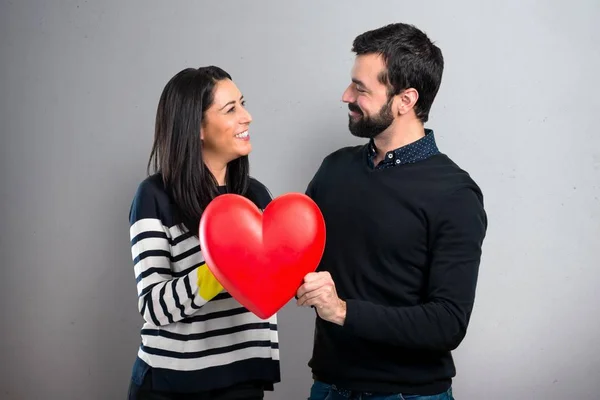 夫妇抱着一个心脏玩具灰色背景 — 图库照片