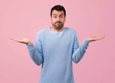 Yakışıklı adam şüpheleri ve pembe bir arka plan üzerinde karıştırmayın yüz ifadesi ile