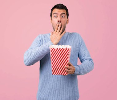 Adam mavi kazaklı popcorns pembe arka plan yemek