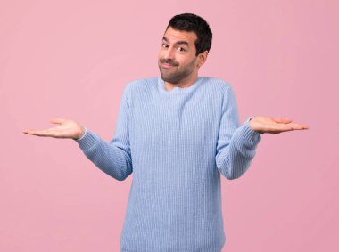 Adam mavi kazak yapımı önemsiz ve pembe bir arka plan üzerinde şüphe jest