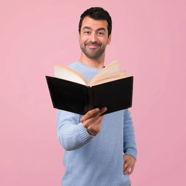 Człowiek Niebieski Sweter Gospodarstwa Czytając Książkę Różowym Tle — Zdjęcie stockowe