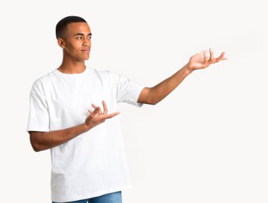 Eller yana uzanan ve sunulması ve yalıtılmış zemin üzerine gelmek için davet için gülümseyen genç Afro-Amerikan adam