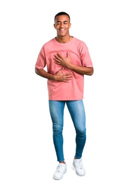 Çok izole beyaz zemin üzerine göğsünde el koyarken gülümseyen genç Afro-Amerikan adam ayakta