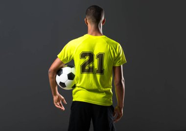 Elleri ile bir topu yakalıyor koyu arka plan üzerinde oynarken futbol oyuncu adam ile koyu derili
