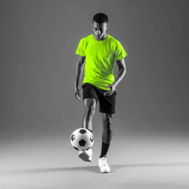 Koyu arka plan üzerinde topu tekmeleme oynarken futbol oyuncu adam ile koyu derili