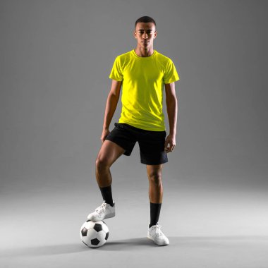 Koyu arka plan üzerinde oynarken futbol oyuncu adam ile koyu derili