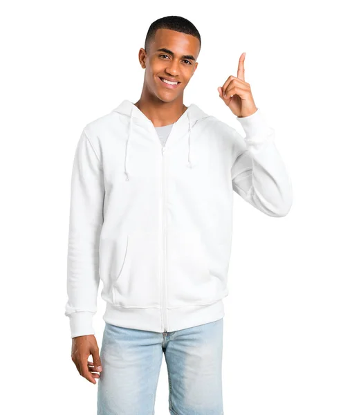 白いトレーナーを表示と分離の白い背景で最高の記号で指を離すと浅黒い肌の若い男 — ストック写真