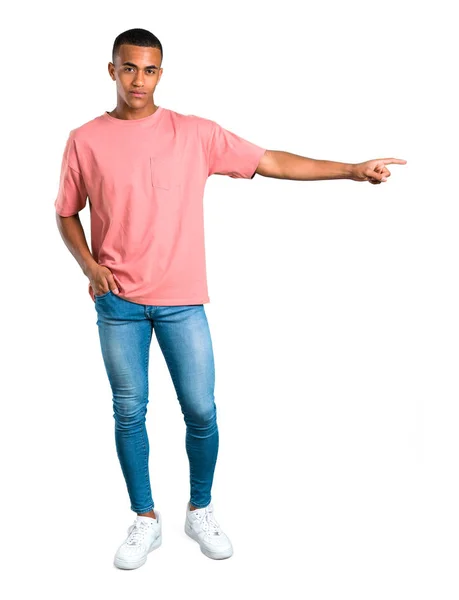 立っている若いアフリカ系アメリカ人の側に指を指していると分離の白い背景の上に製品を提示 — ストック写真