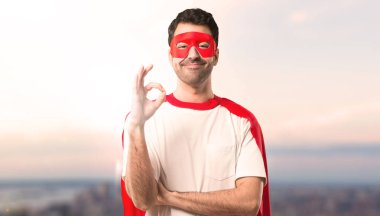 Süper kahraman maske ve kırmızı pelerin parmaklar ok işaretiyle gösterilen adamla. Mutluluk ve memnuniyet günbatımı arka plan yüzü
