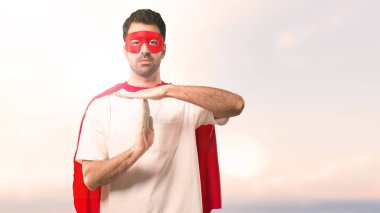 Gün batımı bir arka plan üzerinde bir hareket durdurmak için maske ve kırmızı pelerin yapma dur jest eliyle adamla süper kahraman