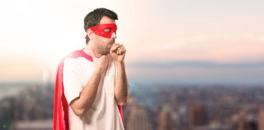 Süper kahraman maske ve kırmızı pelerin adamla öksürük ile acı ve gün batımı bir arka plan üzerinde kötü hissediyor