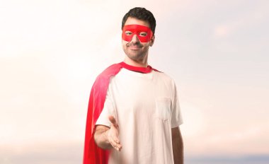 Süper kahraman maske ve kırmızı pelerin günbatımı bir arka plan üzerinde iyi bir anlaşma kapanış tokalaşırken adamla