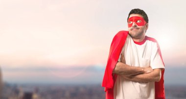 Süper kahraman maske ve kırmızı pelerin önemsiz yapma ve şüpheler adamla jest günbatımı bir arka plan üzerinde omuz kaldırma sırasında