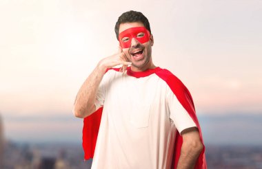 Süper kahraman adam telefon jest yapma ve biriyle konuşma maskesi ve kırmızı pelerin. Bana bir gün batımı arka plan üzerinde arka işareti de