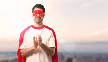 Süper kahraman maske ve kırmızı pelerin günbatımı bir arka plan üzerinde bir konferansta sunum sonrası applauding adamla