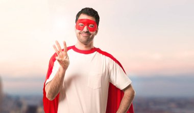 Süper kahraman maske ve kırmızı pelerin mutlu ve sayım üç gün batımı bir arka plan üzerine parmağınızla adamla