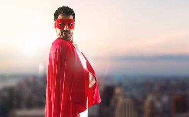 Süper kahraman maske ve kırmızı pelerin kolları adamla günbatımı bir arka plan üzerinde çarpı işareti