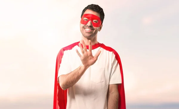 スーパー ヒーロー マスクと赤マントは 夕日を背景に指で を数える男 — ストック写真