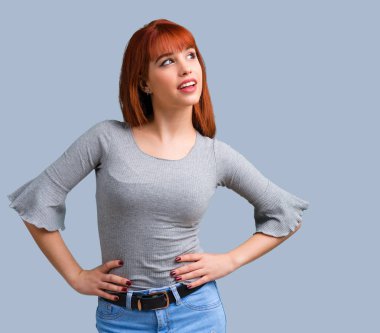 Silah, kalça üzerinde mavi arka plan ile poz genç Kızıl saçlı kız