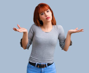 Genç Kızıl saçlı kız şüpheleri ve mavi arka plan üzerinde karıştırmayın yüz ifadesi ile