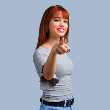 Genç Kızıl saçlı kız puan parmak size mavi zemin üzerine